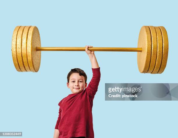 cute child lifting gold barbell on blue pastel background. he is a determined and successful child. - young kid and barbell stock pictures, royalty-free photos & images