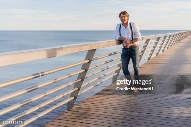 man leaning on railing on a jetty - lean imagens e fotografias de stock