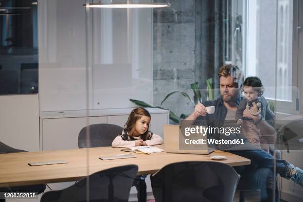 casual businessman with two daughters working at desk in office - kompatibilität stock-fotos und bilder