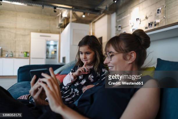 woman and girl sitting on couch in office using smartphone - dinge die zusammenpassen stock-fotos und bilder