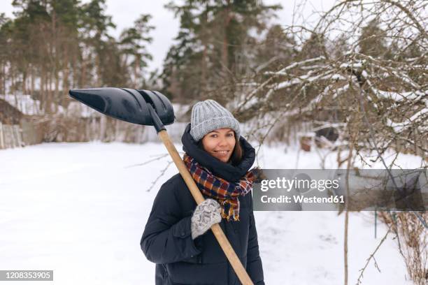 portrait of smiling woman with snow shovel - shoveling snow stock pictures, royalty-free photos & images