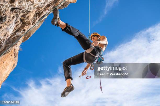 female climber abseiling from rock face - woman climbing rope stock-fotos und bilder