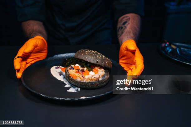 close-up of chef presenting a burger dish in restaurant kitchen - personal chef stock pictures, royalty-free photos & images