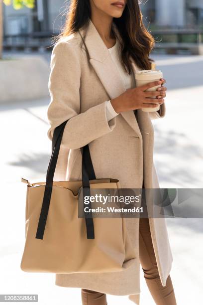 young woman with takeaway coffee on the go in the city - cream colored purse 個照片及圖片檔