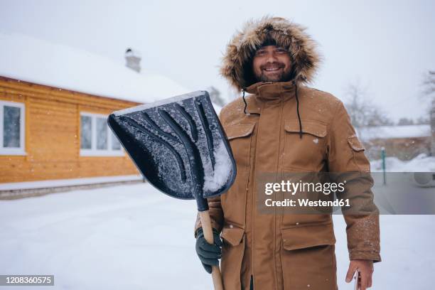 portrait of smiling man with snow shovel - winter snow shovel stock pictures, royalty-free photos & images