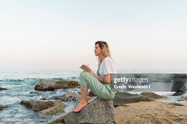 young woman spending a day at the seaside, writing in her diary - woman writer stock pictures, royalty-free photos & images