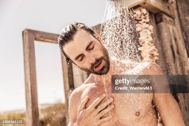 young man taking a shower in an outside shower - hombre en la ducha fotografías e imágenes de stock
