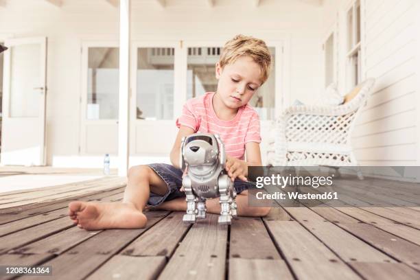 boy playing with robot dog on veranda - friends loneliness stock-fotos und bilder