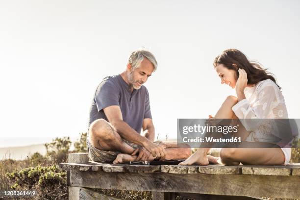 couple sitting on boardwalk at the coast playing backgammon - backgammon 個照片及圖片檔