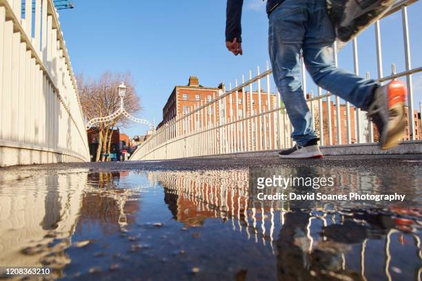 ha'penny bridge reflected in a puddle in dublin city, ireland - ha'penny bridge dublin stock pictures, royalty-free photos & images