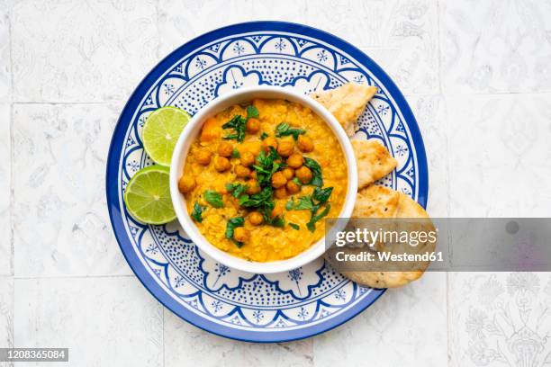 vegan lentil curry with red lentils, sweet potatoes, spinach, roasted turmeric, chickpeas, with lime juice and coriander and naan bread - lentil stock-fotos und bilder