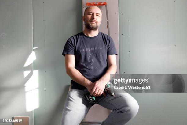 portrait of confident man holding portable drill on construction site at home - portrait man building stock pictures, royalty-free photos & images