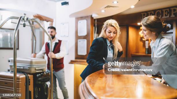 businesswoman checking in at the hotel reception - bus boy stock pictures, royalty-free photos & images