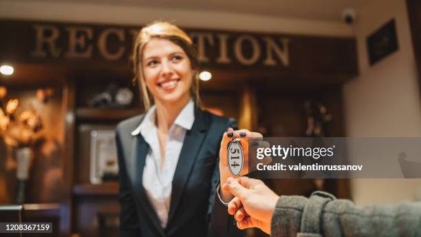 man just arriving in hotel and receiving keys from his room after check-in - hotel key stock pictures, royalty-free photos & images