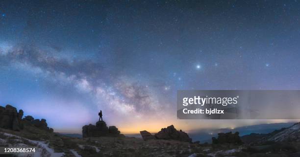 un hombre de pie junto a la galaxia de la vía láctea - milky way fotografías e imágenes de stock