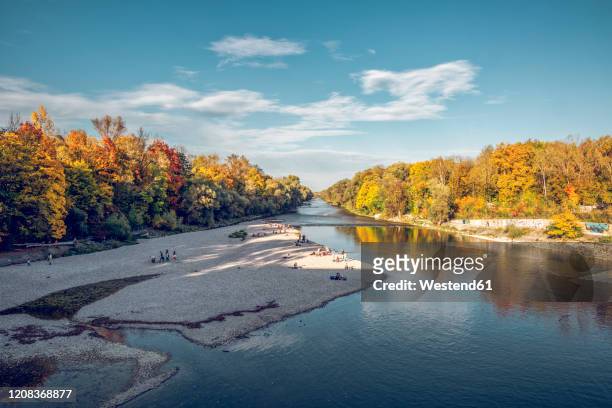 people relaxing at isar river in northern english garden in autumn, oberfohring, munich, germany - munich autumn stock pictures, royalty-free photos & images