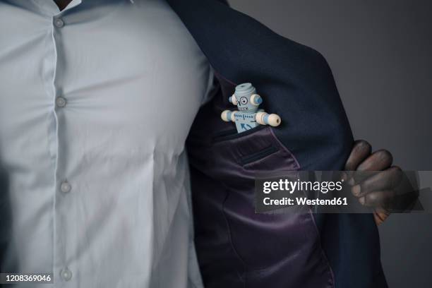 crop view of businessman with toy robot in his jacket pocket - jacket stock pictures, royalty-free photos & images