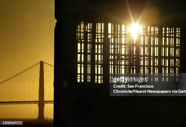 ALCATRAZ_0662_fl.jpg The setting sun beams through a maze of prison bars on the west end of the island with the Golden Gate Bridge in the background....