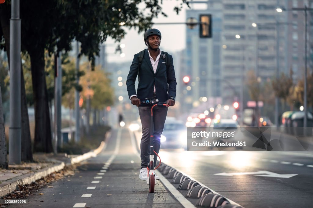 Portrait of businessman riding push scooter on bicycle lane in the evening
