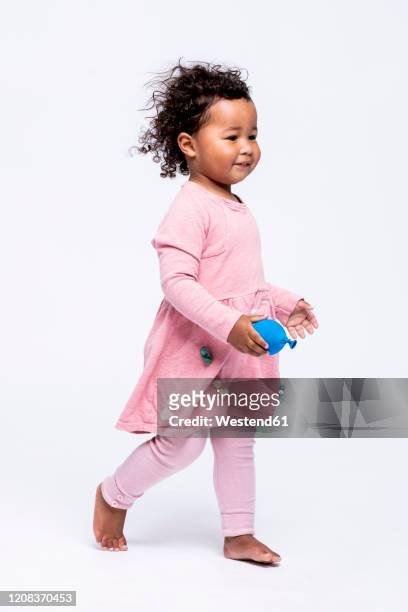 portrait of barefoot little girl dressed in pink walking in front of white background - little black dress stock-fotos und bilder