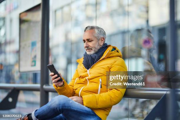 mature man using cell phone in the city - warm clothing stock pictures, royalty-free photos & images