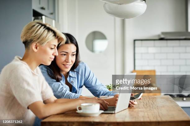 lesbian couple with laptop on table at home - see stock pictures, royalty-free photos & images