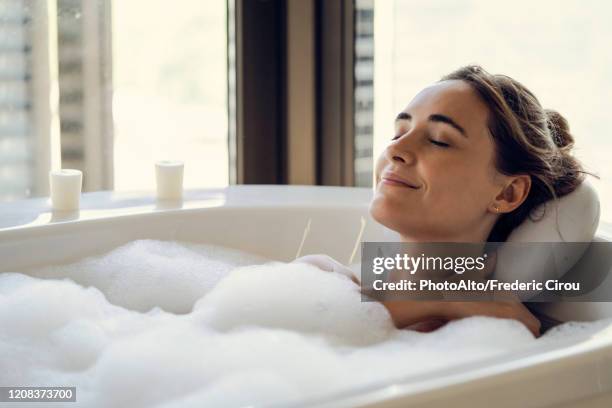 young woman relaxing in bathtub - badeschaum stock-fotos und bilder