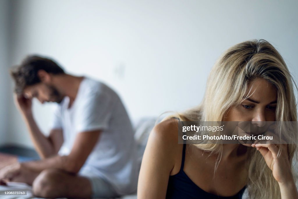 Upset couple sitting in bedroom