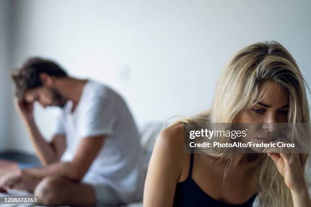 upset couple sitting in bedroom - relatieproblemen stockfoto's en -beelden