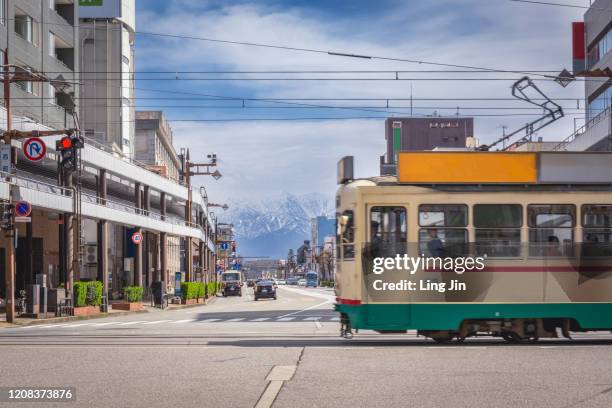 a tram train passing the street in toyama city - 富山県 ストックフォトと画像