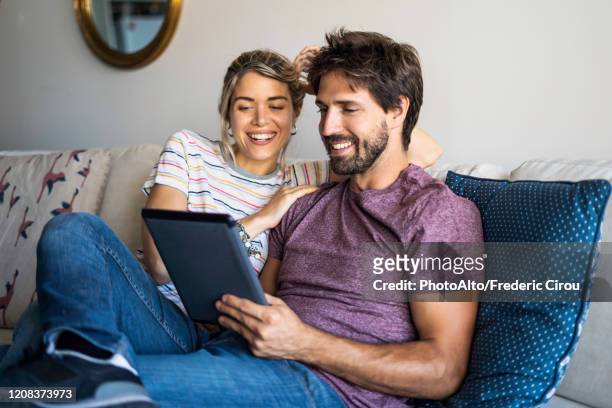 couple using digital tablet at home - couple photos et images de collection