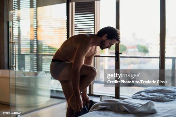 young man getting dressed at home - ondergoed stockfoto's en -beelden