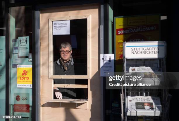 March 2020, Baden-Wuerttemberg, Stuttgart: Volker Suchanek, owner of the retail store Abele Tabakwaren, stands behind a protection of wood and...