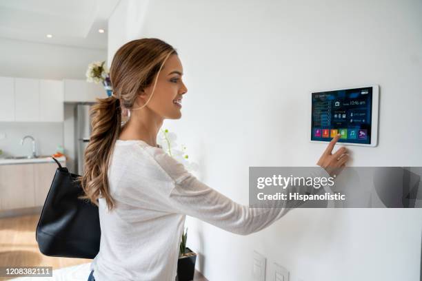 hermosa mujer activando un sistema de cerradura en su casa inteligente sonriendo - connected home fotografías e imágenes de stock