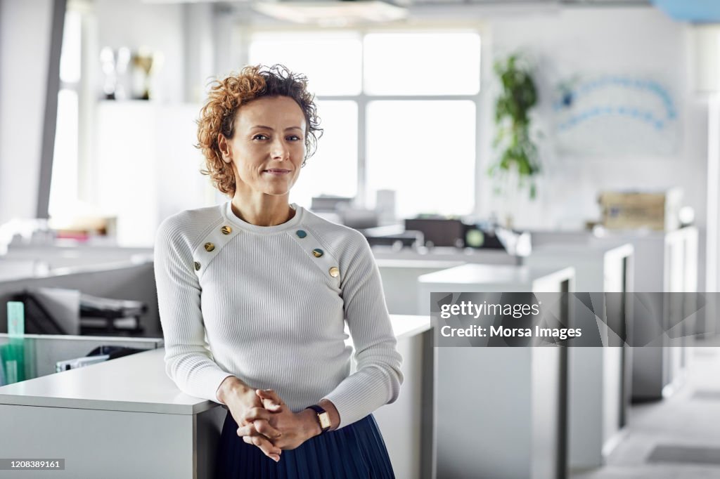 Confident businesswoman with hands clasped