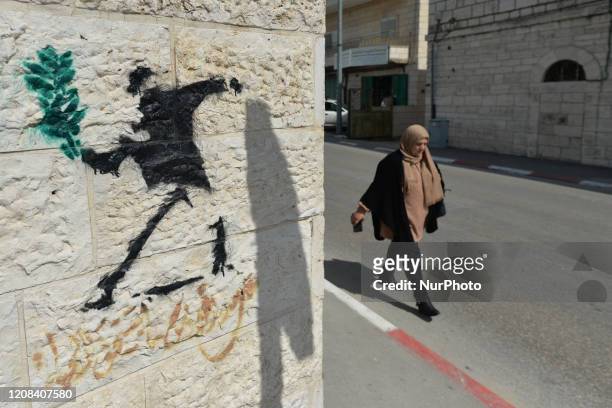 Lady walks by a politicalgraffiti near the wall separting Israel and the West Bank in Bethlehem. On Thursday, March 5 in Bethlehem, Palestine