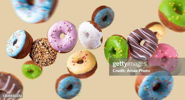 bunte donuts fliegen auf gelbem hintergrund. süßes essen hintergrund. - doughnuts stock-fotos und bilder