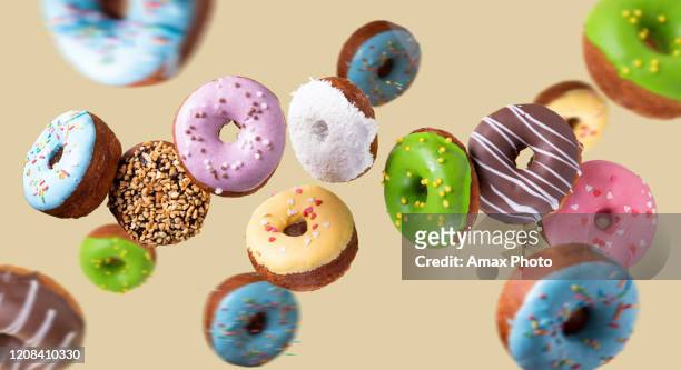 colorful donuts flying on yellow background. sweet food background. - donut stock pictures, royalty-free photos & images