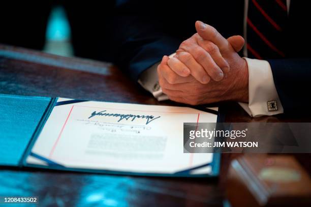 President Donald Trump signs the CARES act, a $2 trillion rescue package to provide economic relief amid the coronavirus outbreak, at the Oval Office...