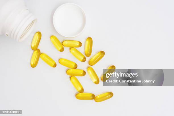 fish oil capsules spilling from bottle - fish oil stockfoto's en -beelden