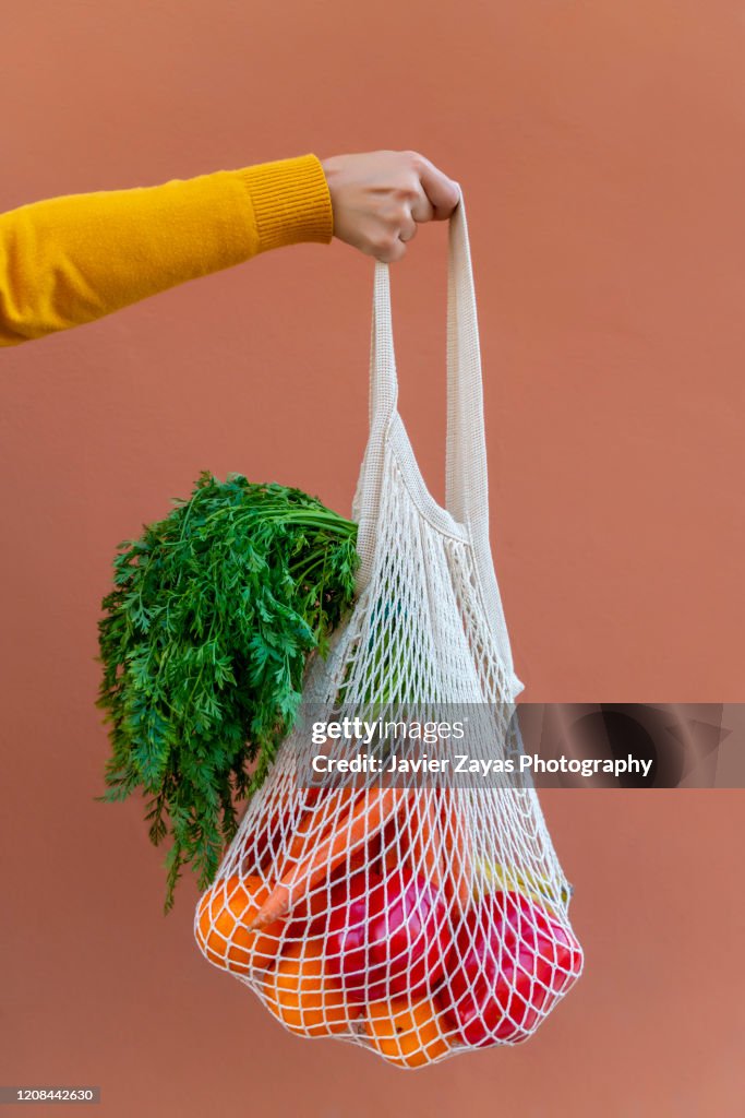Woman Holding Reusable Cotton Mesh Bag With Fruit And Vegetables