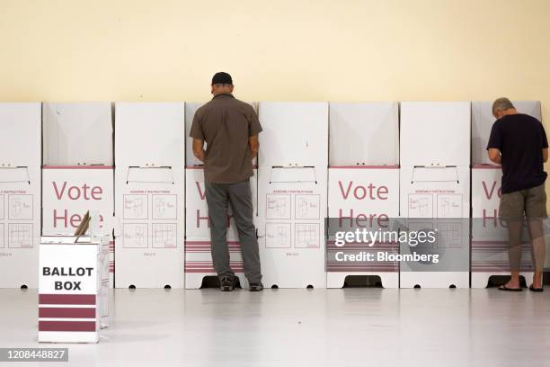 Voters fill their ballots at voting booths, spaced apart to enforce social distancing measures due to the coronavirus, at a polling station during...