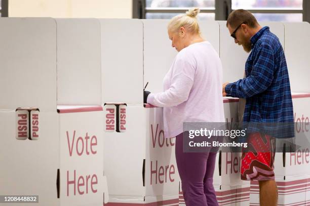 Voters fill their ballots at voting booths, spaced apart to enforce social distancing measures due to the coronavirus, at a polling station during...