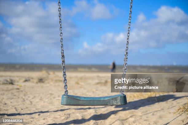 March 2020, Lower Saxony, Dangast: The swing of the closed playground at the beach remains unused. Photo: Mohssen Assanimoghaddam/dpa