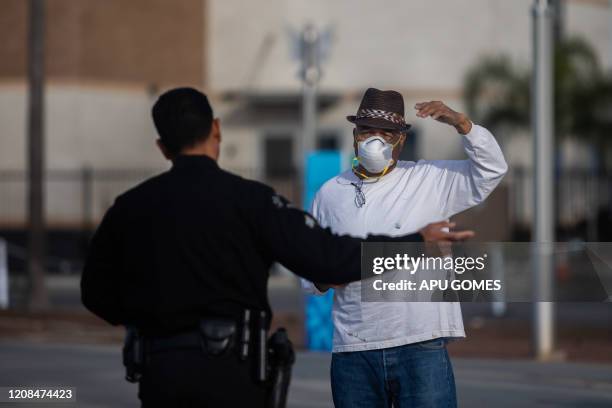 Police officer talks to a man wearing a facemak as a preventive measure against the spread of the COVID-19 novel coronavirus on March 28, 2020 at the...