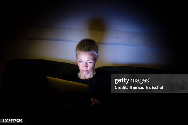 Symbol photo on the subject of loneliness and isolation: A woman sits on the couch at night and looks into her laptop on March 25, 2020 in Berlin,...