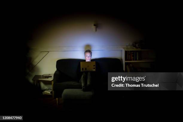 Symbol photo on the subject of loneliness and isolation: A woman sits on the couch at night and looks into her laptop on March 25, 2020 in Berlin,...