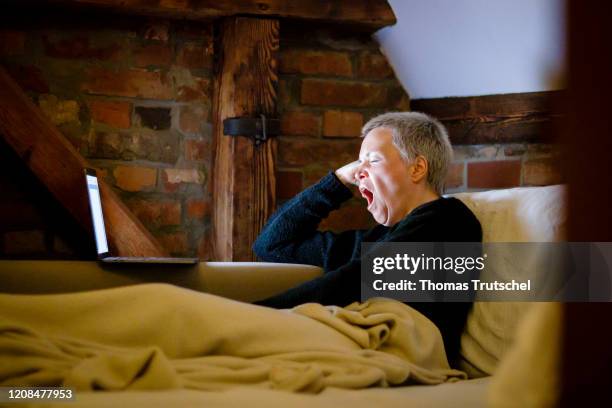 Symbol photo on the subject of video streaming. A woman lies on the couch, looks into her laptop and yawns on March 25, 2020 in Berlin, Germany.