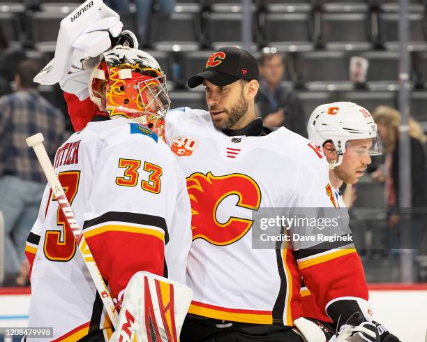 David Rittich of the Calgary Flames is congratulated by teammate Cam Talbot after an NHL game against the Detroit Red Wings at Little Caesars Arena...