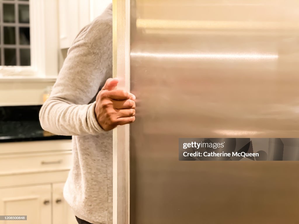 African-american woman standing at open refrigerator